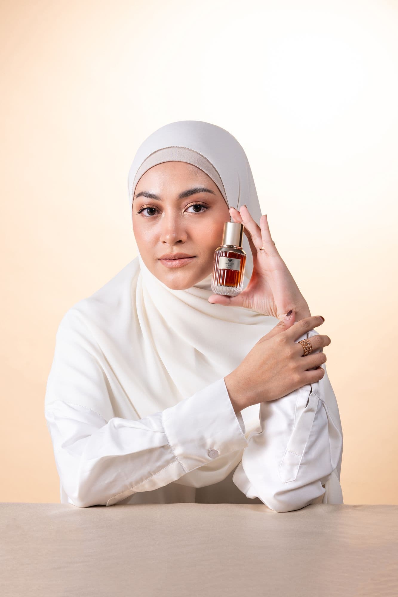 Model holding a Beauboss perfume bottle beside her face
